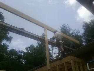 Carpenter setting a ridge beam over a new addition frame — Ice Dam Removal by Roofing Brothers in Buda
