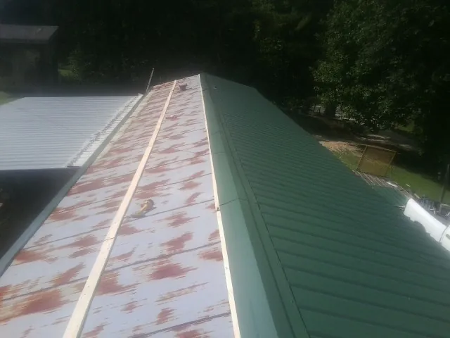 Old rusted panels beside newly installed green metal roofing — Wind Damage Roof Repair by Roofing Brothers in Buda