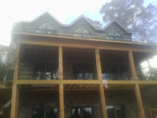 Dormers and porch framing on a large log home under construction — Roof Coating work by our crew in Buda