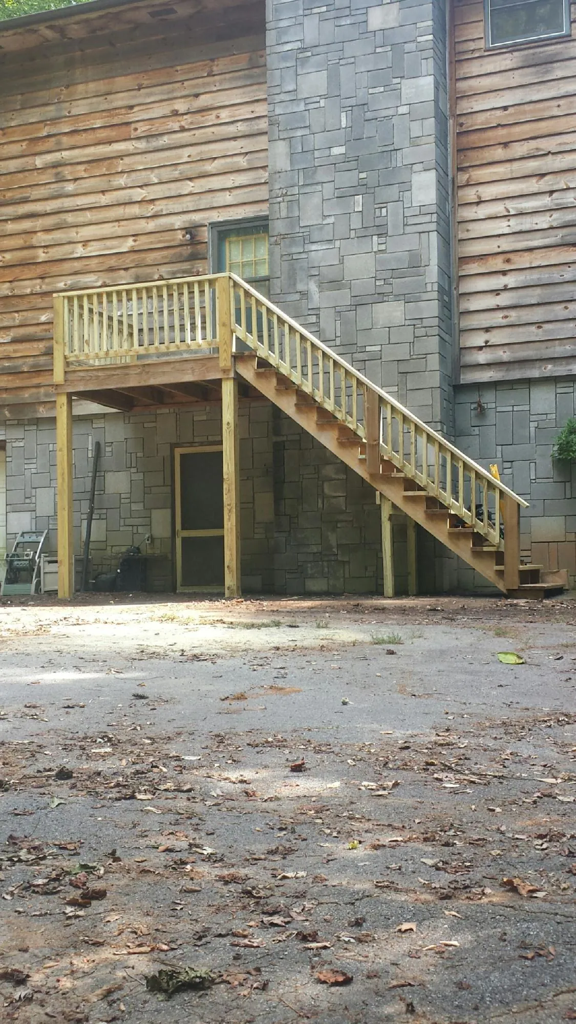 New pressure treated deck and stair landing on a log home in Buda