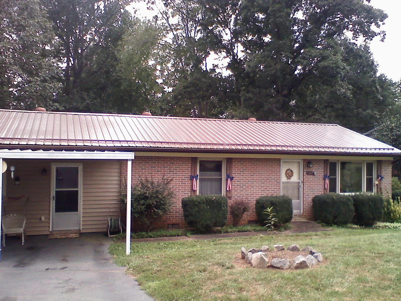 Bronze metal roof and carport on a brick ranch home — Roof Repair work by our crew in Buda