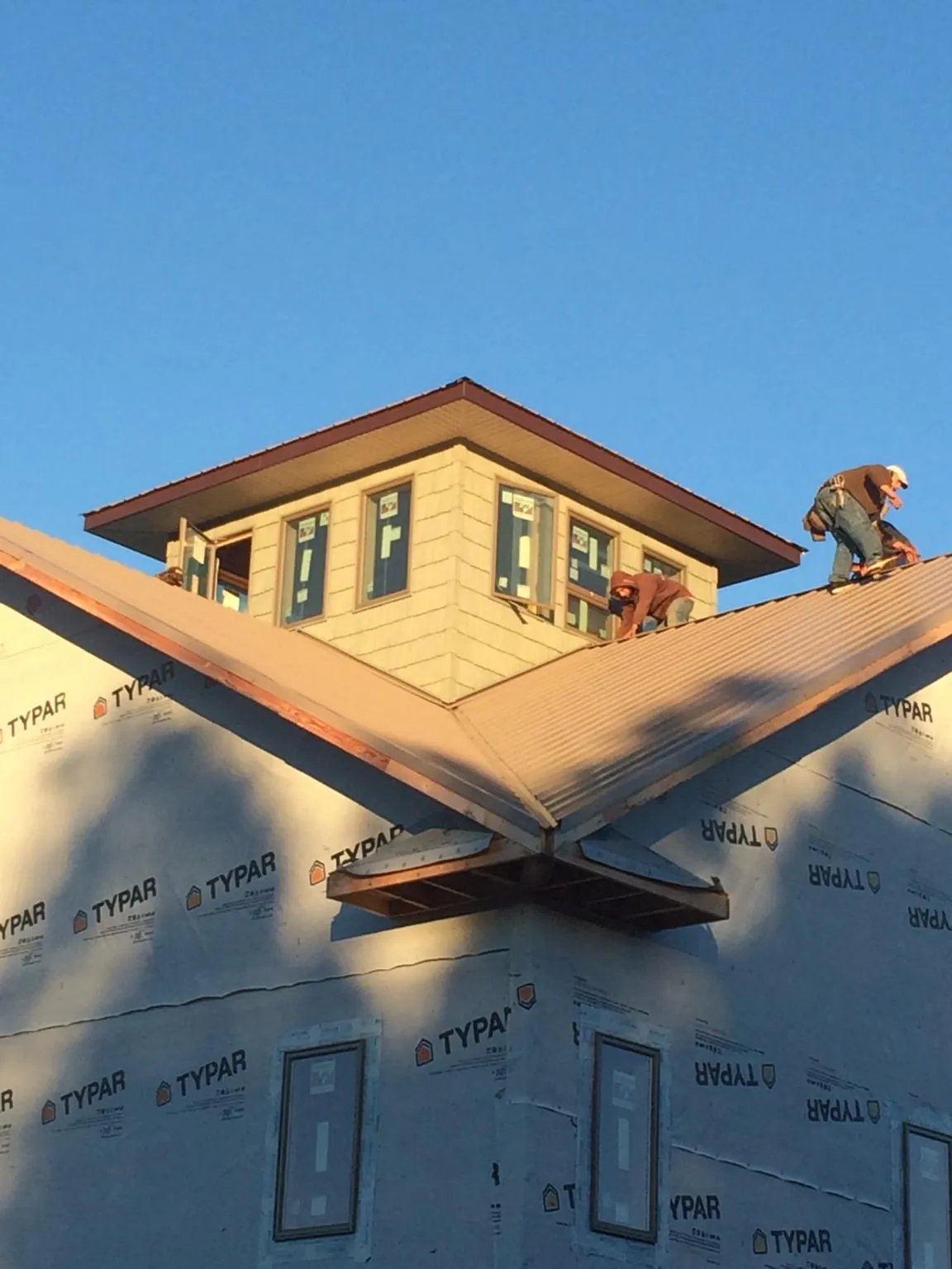 Roofers working around a rooftop cupola on a new metal roof at sunset — Roof Waterproofing in Buda by Roofing Brothers